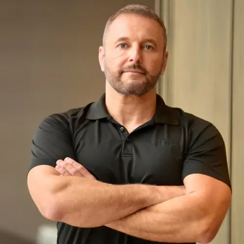 Alex Samoylovich, founder and real estate executive, in a black polo shirt with arms crossed.